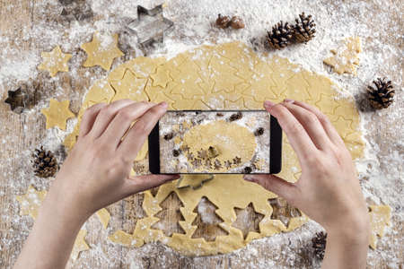 A high angle shot of a person taking a picture of a flattened dough with a smartphone
