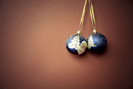 A closeup shot of two blue Christmas tree hanging ornaments on a brown surfaceの写真素材