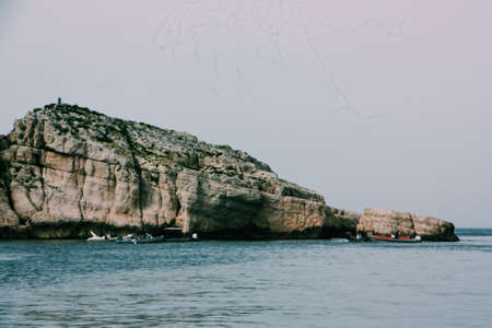 A wide shot of a cliff by the water under a clear skyの写真素材