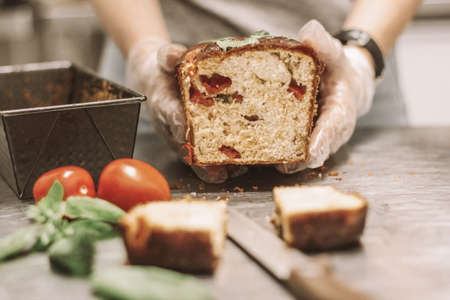A close shot of chef's holding a loaf of bread near tomatoes with a blurred background