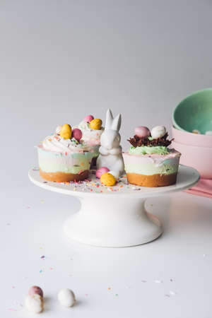 A vertical shot of Easter bunny and cupcakes on a white ceramic cake standの写真素材