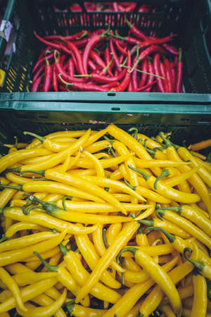 A vertical high angle shot of boxes of red and yellow peppers in a vegetable market