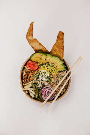 An overhead shot of a bowl of food with chopsticks