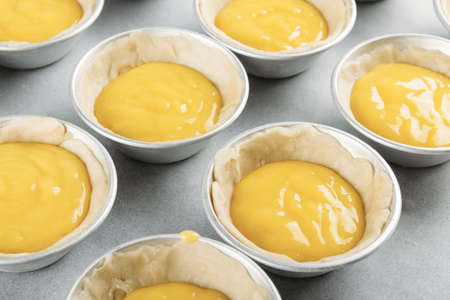 A high angle shot of unbaked cookie dough in the cupcake mold on a metal surface