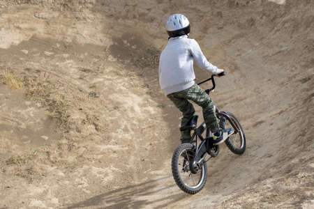 A young male riding a bicycle in a brown field