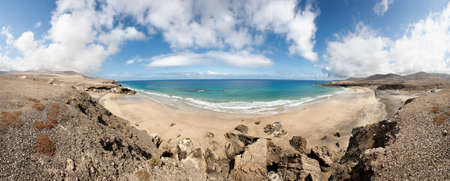A panoramic shot of a scenic beach with turquoise water under a cloudy skyの写真素材
