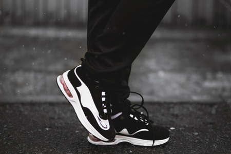 A vertical selective closeup shot of a person wearing  black and white sneakers