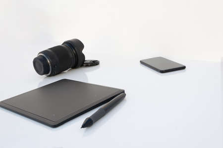 A mobile composition with a photographic lens and graphic tablet isolated on white backgroundの写真素材