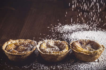 A high angle shot of three homemade muffins decorated with sugar powder on a wooden surfaceの写真素材