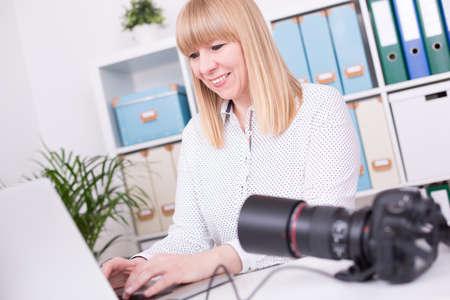 A young Caucasian female photographer working in the officeの写真素材
