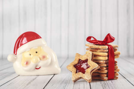 A closeup shot star shaped christmas cookies next to a decorative santa head put on a wooden surfaceの写真素材