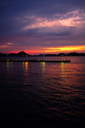 A beautiful vertical shot of the sunset reflected in the water under the cloudy skyの写真素材