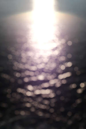 A vertical blurry shot of the sun reflected in the water