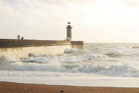 A beautiful shot of a tall lighthouse tower beacon at the shore of the sea with strong waves