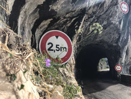 A wide shot of signs near a tunnel route under an arch rock