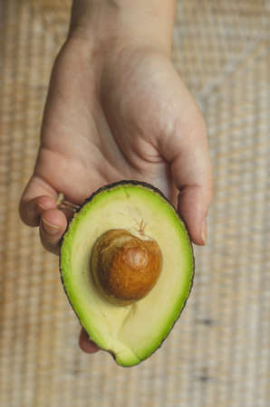 A vertical shot of a person holding sliced avocado