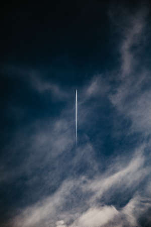 A vertical shot of a plane flying in a cloudy sky