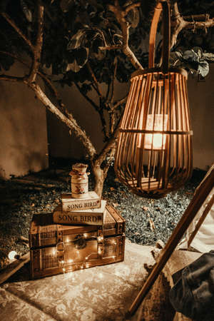 A horizontal shot of a wooden lampshade and a wooden chest with books on it placed in a gardenの写真素材