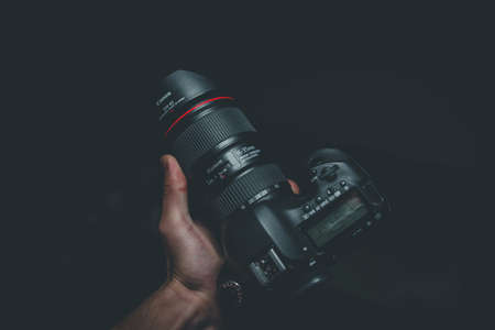 A close shot of a person holding a camera with a black backgroundの写真素材