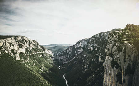 An aerial shot of a river in the middle of forested mountains under a cloudy sky at daytime