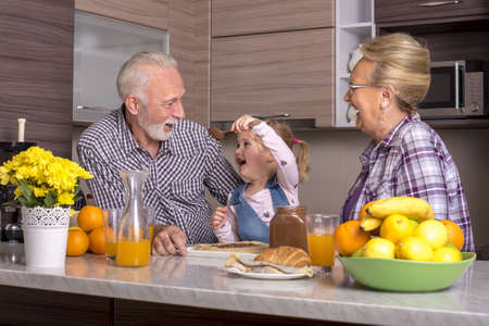 A little girl making pancakes with her grandparentsの写真素材