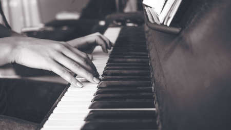 A greyscale shot of a female playing the piano