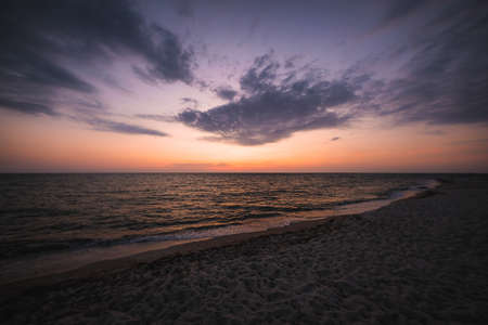 A beautiful shot of a beach shore under an orange and blue sky at sunset