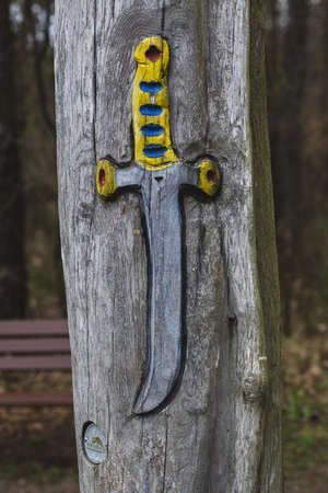 A piece of wood with a grey and yellow dagger sculpture