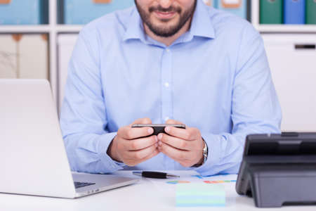 A Caucasian man looking at his phone in the office