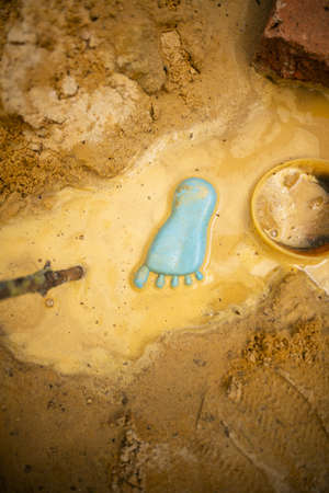 A vertical shot of a blue footprint toy in sandy water near sandsの写真素材