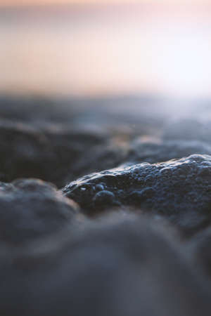A vertical selective focus shot of rock with water drops on it and a blurred background
