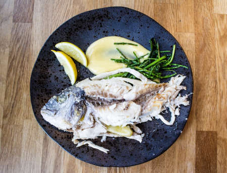 An overhead shot of a raw fish with lemons on a round plate