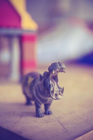A vertical closeup focus shot of a hippo toy with a blurred background n the edge of the table