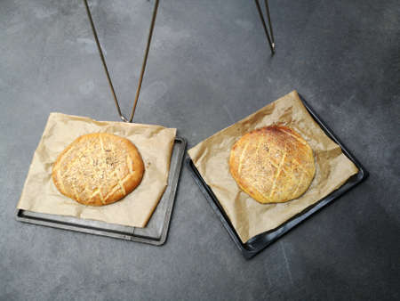 A fresh flatbread with baking paper on the baking sheet on a gray concrete floor
