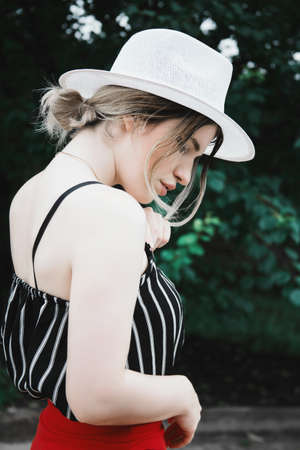 An attractive sensual female model in a striped top and red holiday pants with a hat in the gardenの写真素材