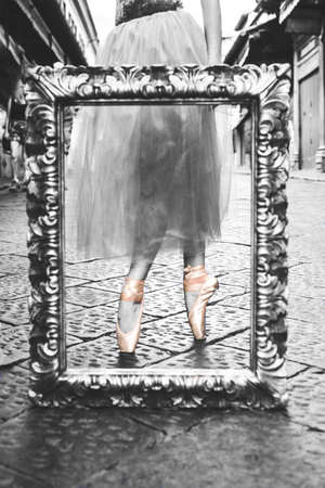 A grayscale vertical shot of a picture frame with ballerina's feet in the frameの写真素材