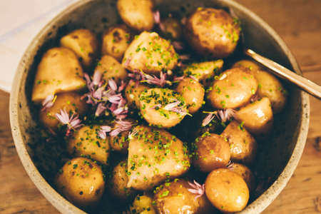 A selective closeup shot of cooked round potatoes in a bowl flavored with cut green onionの写真素材