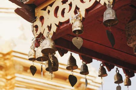 A closeup shot of brass bells hanging from an Asian temple roofの写真素材