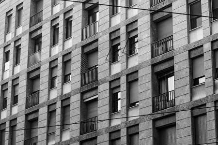 A grayscale shot of a long building with windows and balconiesの写真素材