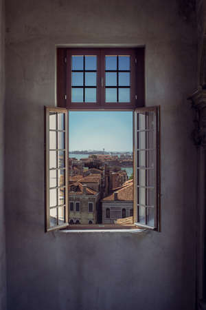 A vertical shot of an opened window with a beautiful view of Venice's cityscape