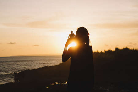A silhouette of a female with the background of the sunset on the beach