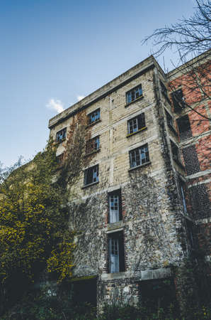 A vertical shot of white brick buildings surrounded with trees under a blue skyの写真素材
