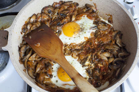An overhead shot of a dish made of mushrooms and eggs in a pan on the ovenの写真素材