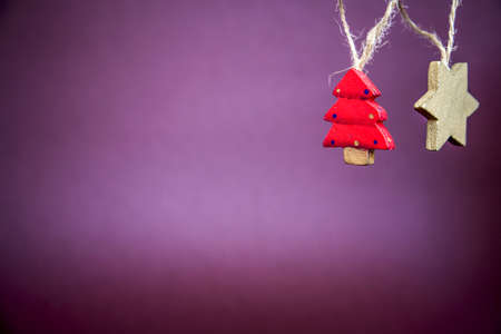 A closeup shot of Christmas tree and star hanging decors with a purple backgroundの写真素材