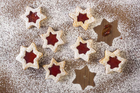 A high angle closeup shit of several star shaped cookies with jam filling set on a table covered in flourの写真素材
