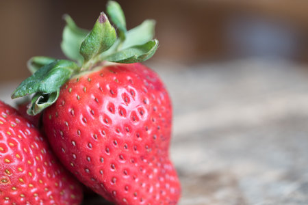 A closeup shot of fresh ripe strawberries on a wooden blurred backgroundの写真素材