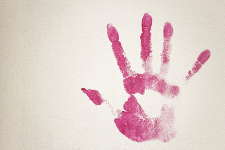 The handprint of a person's hand dipped in pink paint and put on a white surfaceの写真素材