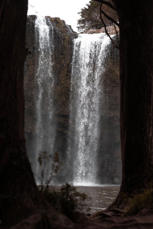 A vertical selective shot of a waterfall flowing down a cliffの写真素材