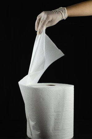 A vertical shot of a male hand wearing a glove getting a paper towel isolated on a black backgroundの写真素材