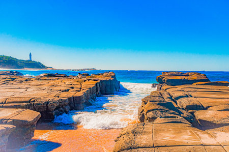 A beautiful scenery of water hitting the rocks and cliffs in the seaの写真素材